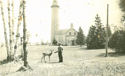 Historical photo of man feeding deer on lighthouse grounds.